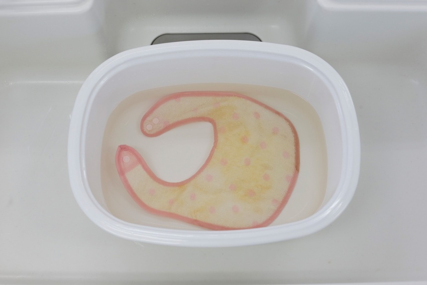 酸素の洗剤サンソリキの溶液にシミ汚れや黄ばんだスタイをつけ置いた写真